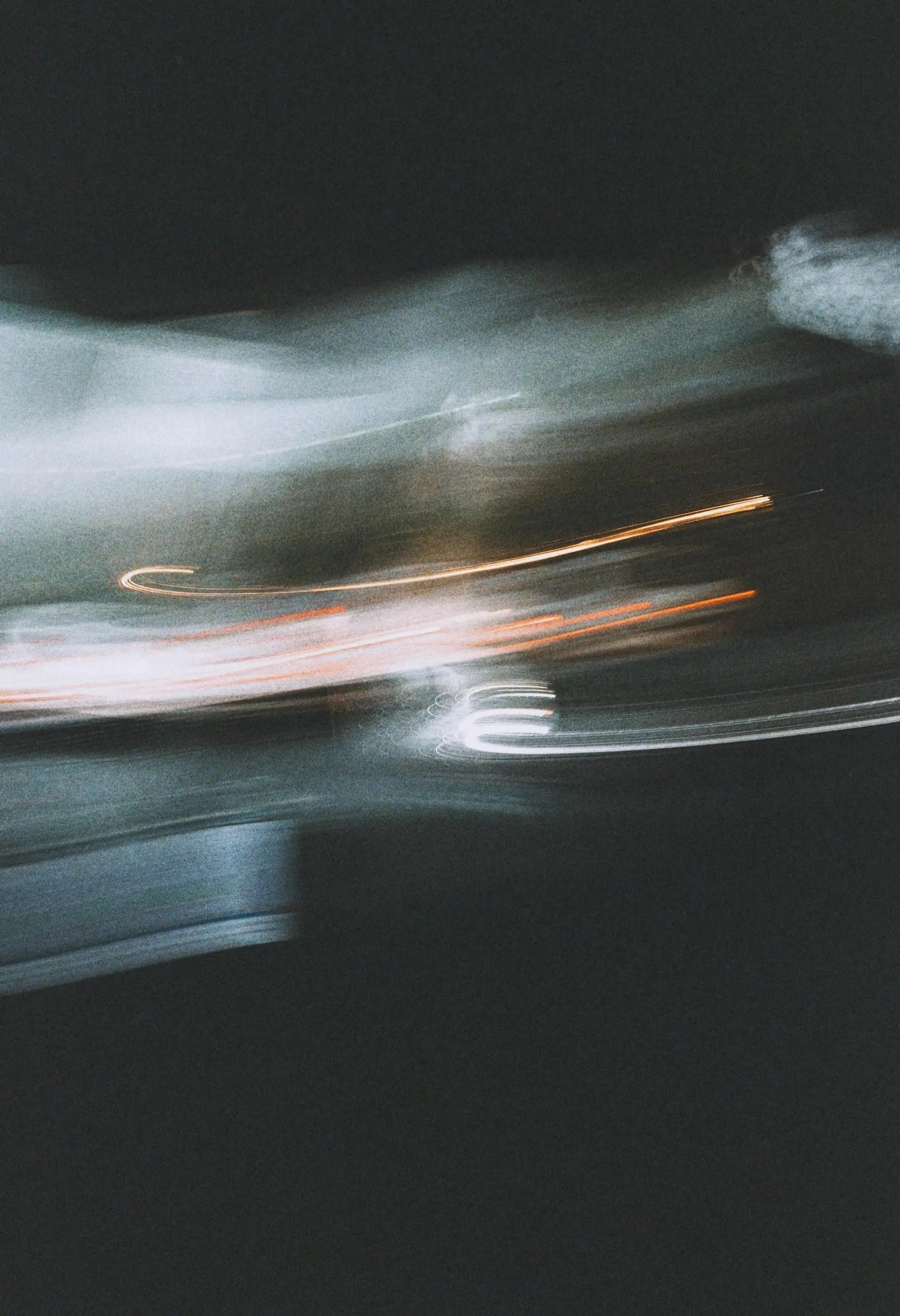 Soft, curling trails of light in motion against dark grey